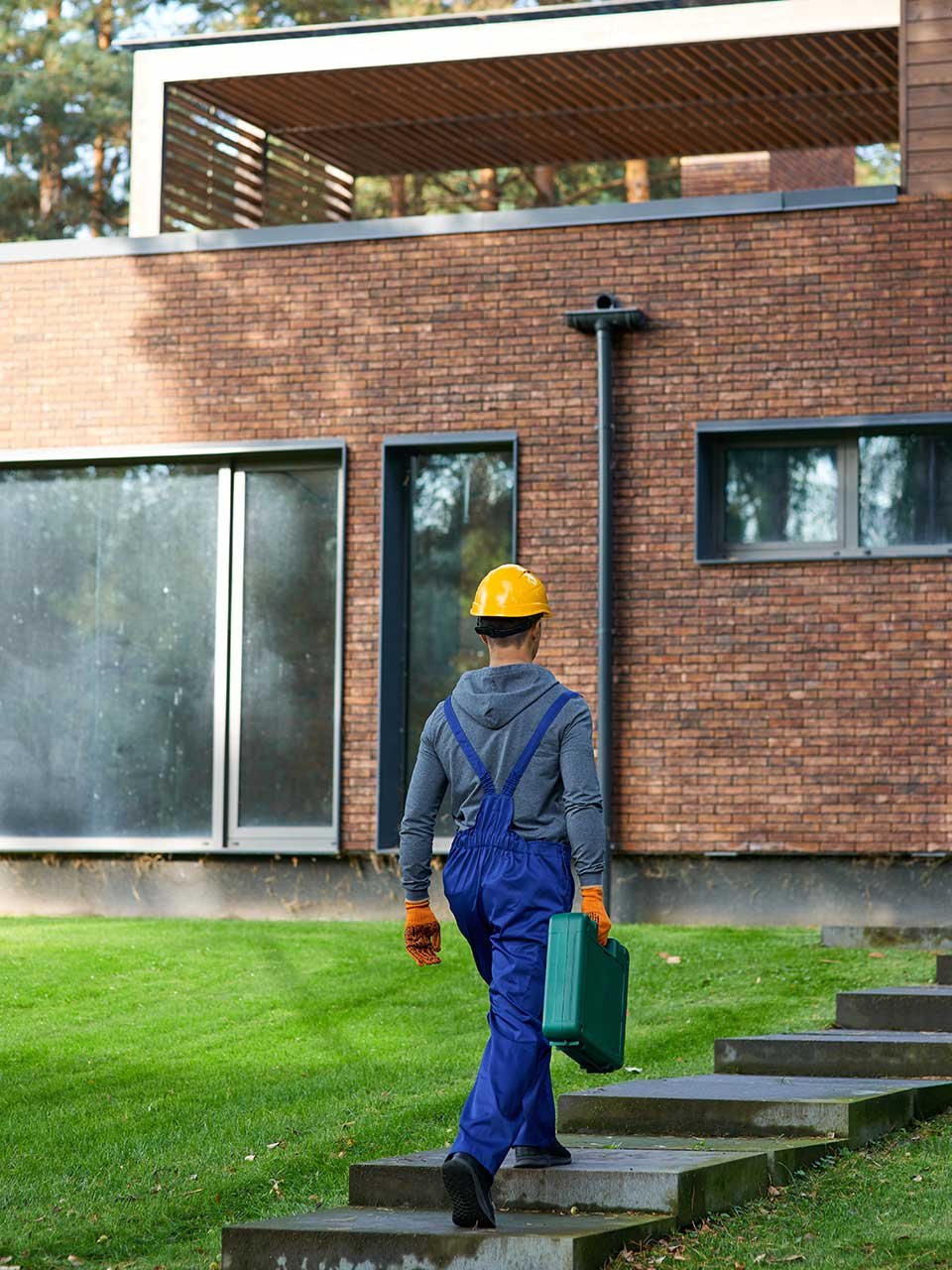 Worker walking to house with toolbox.